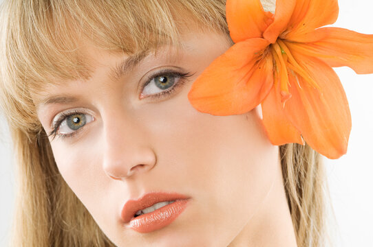 nice clode up of a young pretty woman with an orange lily between hair