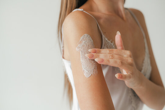 Anonymous woman smearing clay mask on arm