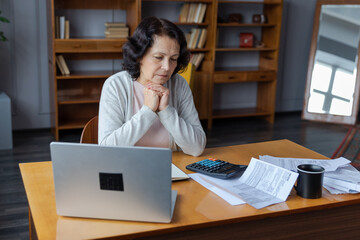 Middle aged senior woman sit with laptop and paper document. Pensive older mature lady reading paper bill pay online at home managing bank finances calculating taxes planning loan debt pension payment - obrazy, fototapety, plakaty