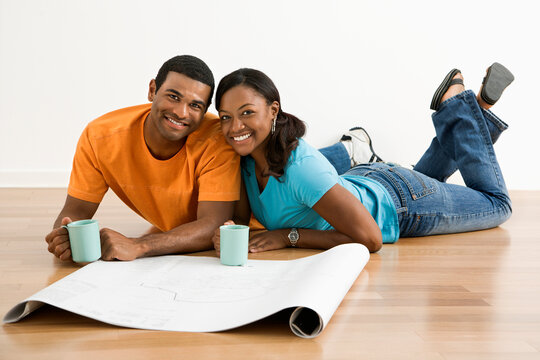 African American male and female couple with architectural  blueprints drinking coffee.