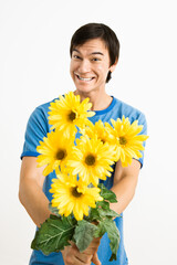 Asian young man holding bouquet of yellow gerber daisies smiling.