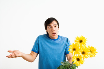 Asian young man holding bouquet of yellow gerber daisies shrugging.