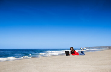 Fototapeta na wymiar Woman working with a laptop on the beach