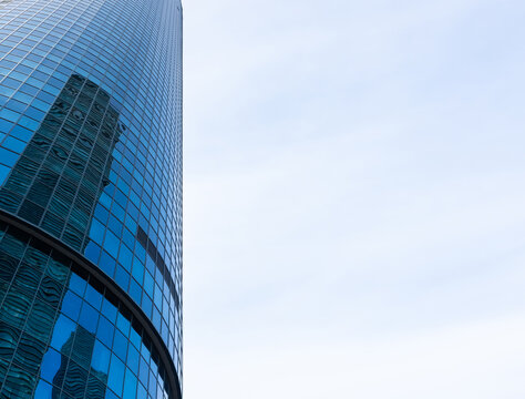 The skyscraper is reflected in the windows of the facade of a modern glass building