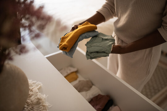 Crop housewife putting clean clothes into commode