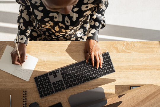 Black influencer writing notes during online work