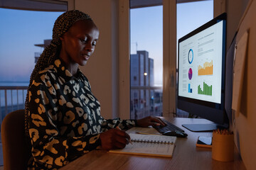 Black businesswoman working with charts on desktop
