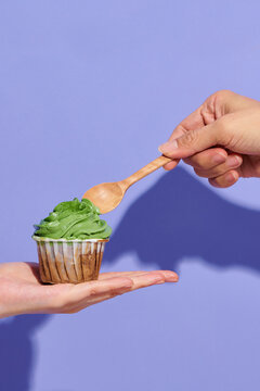 Hand holding a spoon to eat delicious cupcake with cream