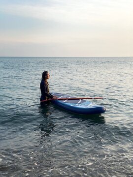 UGC woman in a wetsuit sports sap surfing the sea at sunset