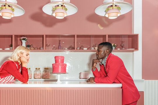 A fashionable married couple looks at an elegant cake in the kitchen