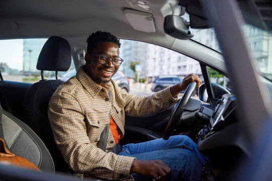 Portrait of happy man sitting in car holding steering wheel