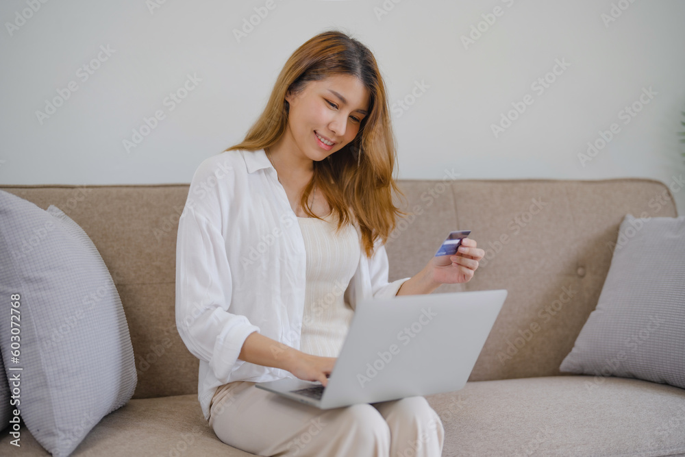 Wall mural Happy asian woman using laptop and credit card for online payment, E-commerce