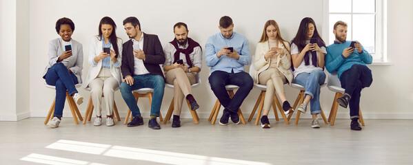 Group of different people using mobile phones. Male and female employees sitting in modern office with wireless Internet connection, looking at cellphone screens, messaging, and scrolling news feed
