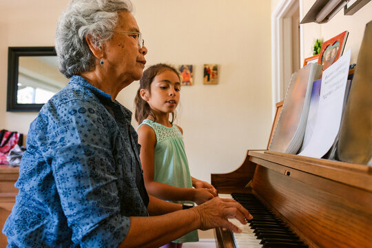 Woman plays piano while grandchild sings at home