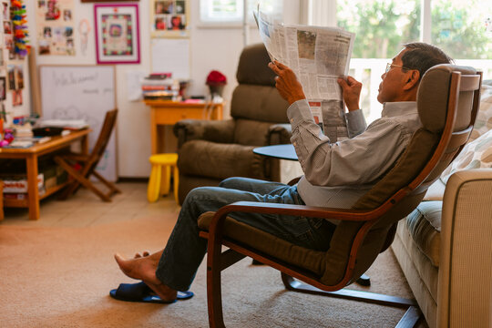 Senior man reading newspaper at home
