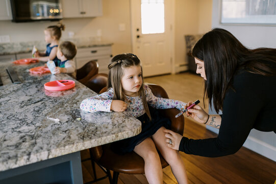 toddler girl with diabetes getting insulin shot in kitchen of her home