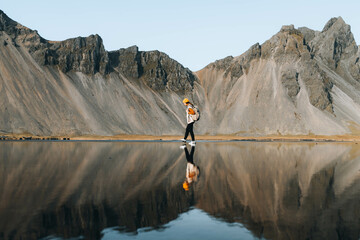 Hiker Girl Walking On Water Surface On Black Sand Beach Reflection.