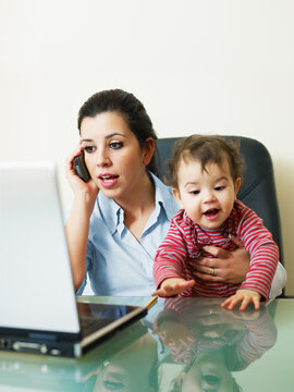 stressed business woman in office, holding her little girl while talking on mobile phone. Vertical shape, Copy space