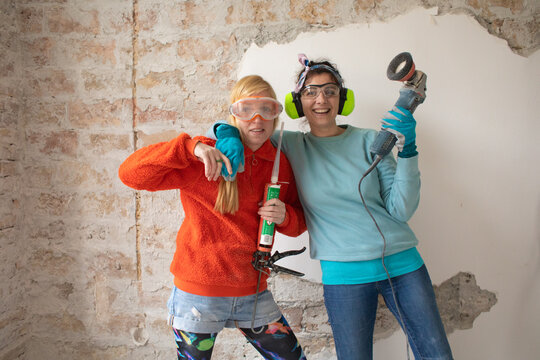 Funny, smiling portrait of two women excited about home renovation