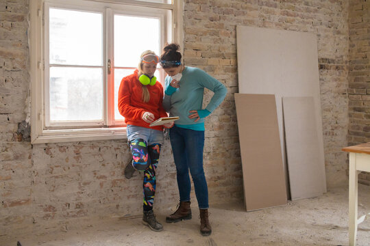Female friends check on the renovation plan on a tablet