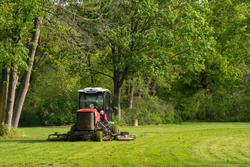 Professional gardener cutting green grass on lawn mower machine in park. High quality photo
