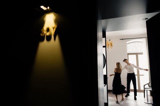 Joyful couple performing dance in hotel room

