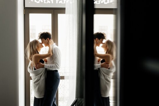 Cheerful couple embracing near window in hotel room
