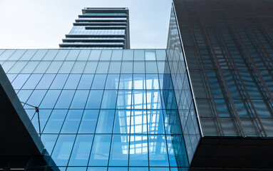 Fototapeta na wymiar The blue sky is reflected in the windows of a modern office building. Architecture and exterior of contemporary houses