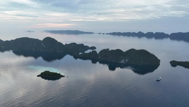 At sunrise, calm seas surround limestone islands that rise from Raja Ampat's dramatic seascape. This remote part of Indonesia is known for its incredibly high marine biodiversity.