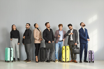 Business people in suits and smart casual clothes standing in a modern train station or airport,...