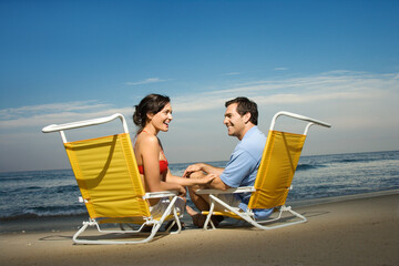Man and woman sit in beach chairs and enjoy one another's company. Horizontal shot.
