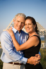 Affectionate couple on beach with their arms around one another. Vertical shot.