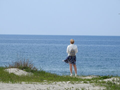 woman in a short skirt with backpack looking in the baltic sea