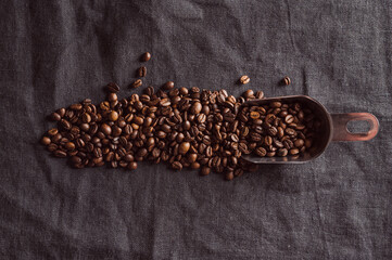 Coffee beans and a spatula on a black linen background