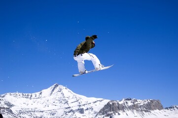 Naklejka na ściany i meble a snowboarder jumping high through a blue sky
