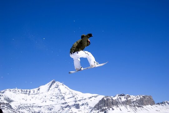 a snowboarder jumping high through a blue sky