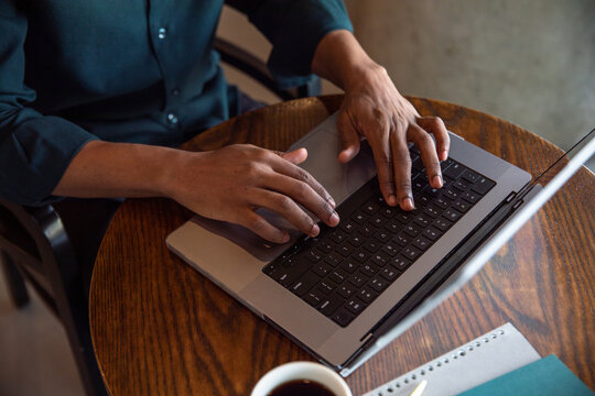 Businessman typing on laptop keypad at cafe