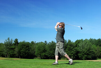 Man tees off at the golf course.