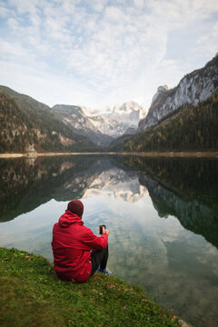 Unrecognizable man with a cup of coffee sitting near lake
