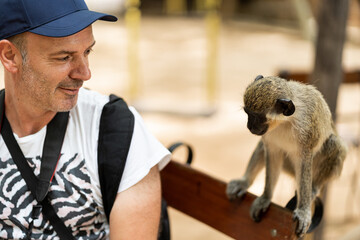 smiling man next to a monkey in the wild