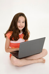 Young girl playing on a laptop computer on a white background