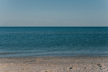 The sea coast with a calm sea against the blue sky