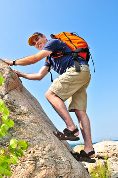 Middle Aged Man With Backpack Climbing A Rock