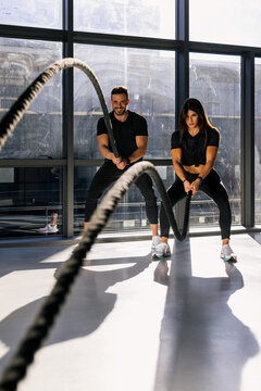 Fitness couple training with battle ropes during functional workout