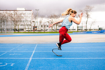 Paralympic woman athlete with bionic leg prosthesis training sprints