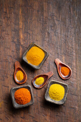 Turmeric, pepper and curry powder in container on wooden background
