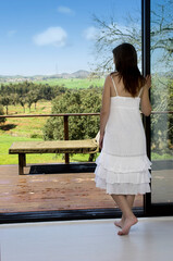 Woman looking to the beautiful green landscape outside of her room