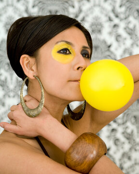 Beautiful asian model with funky make-up blow balloon