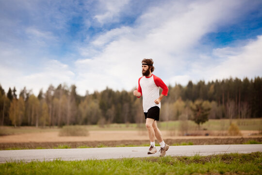 A runner with long hair and beard jogging in the country