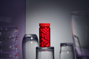 Red bottles transparent with pills capsules on gray background